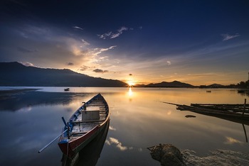small boat on shore at sunset